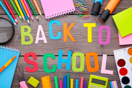 Inscription back to school with school supplies on gray background education