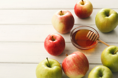 Seasonal autumn background honey and lots of ripe apples on white wooden table with copy space