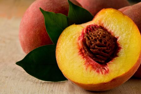 Photo of delicious peaches on wooden table with leaves