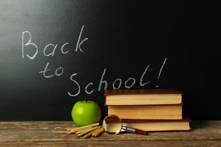 School books on desk near chalkboard Stock Photo