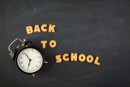 Back to school on a dark background letters alarm clock chalk copy space top view Stock Photo