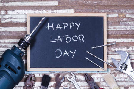 Chalk board with text happy labor day with variety gruge rusty handy tools on a rusty wooden table