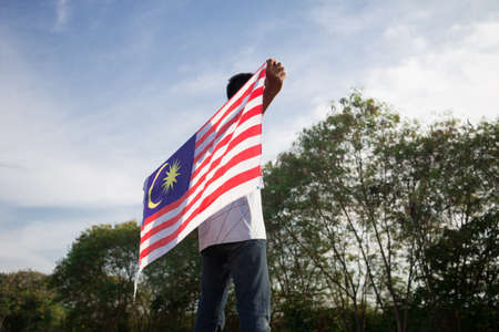 Independence day concept a happy and proud boy holding malaysian flag sky background