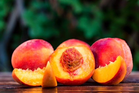 Fresh ripe peaches and slices on wooden table