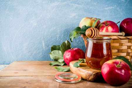 Jewish holiday rosh hashanah or apple feast day concept with red apples apple leaves and honey in jar light blue and wooden background copy space