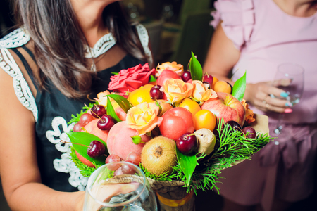 Bouquet flowers and fresh citrus fruits wrapped in coarse paper in hands