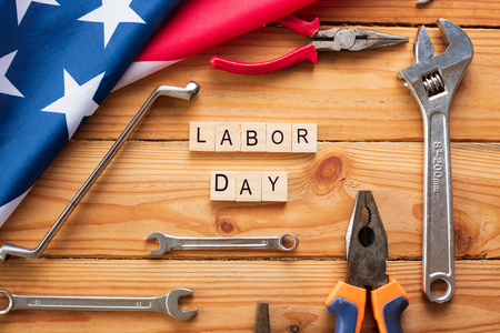 Usa labor day concept first monday in september different kinds on wrenches handy tools america flag and wooden blocks on wooden table Stock Photo