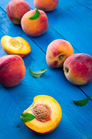 Ripe peaches with mint on blue wooden background Stock Photo