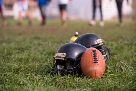 American football helmets and ball lying on field Stock Photo