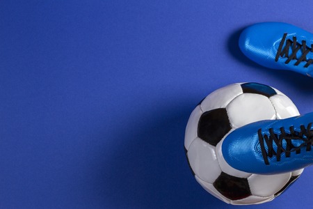 Soccer ball under soccer players feet on blue background Stock Photo