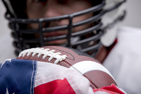 American football ball with the national flag with defocused player on background