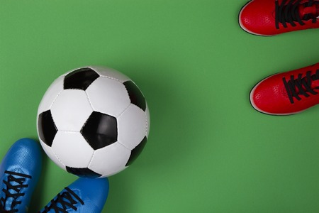 Top view to soccer ball between soccer players feets on green background