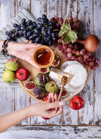 Home made ricotta cheese served with fresh fruit figs nectarines grapes and pears decorated with honey and napkin over a rustic wooden board top view