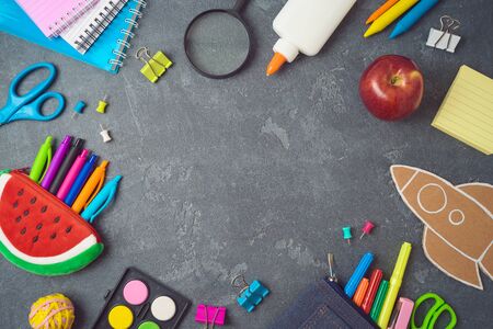 Back to school background with school supplies on blackboard top view from above