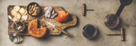 Wine and snack set flat lay of two glasses of red wine vintage corkscrews cheese and appetizers on board over concrete Stock Photo