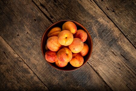 Delicious ripe apricots in a wooden bowl on the table close up horizontal view from above