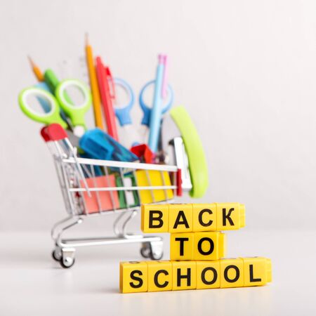 Buy online back to school text of cubes with office supplies in shopping cart on white background Stock Photo