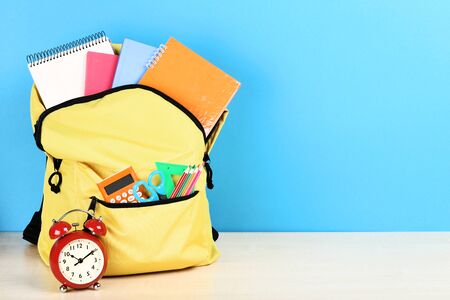 Backpack with school supplies on blue background