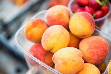 Close view fresh delicious peaches in plastic container for sale in local market organic summer vegetarian food