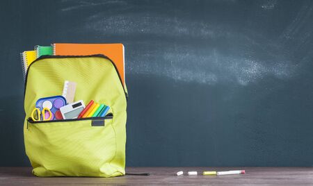 Backpack with school supplies front on the chalkboard