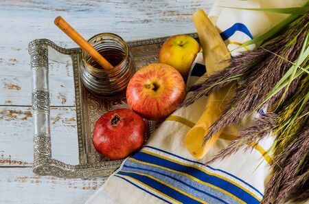 Rosh hashanah jewesh holiday concept shofar honey apple and pomegranate over wooden table