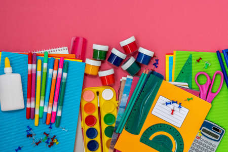 Overhead shot of school supplies on pink background