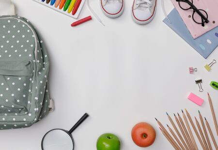 Creative flatlay of education white table with backpack student books shoes colorful crayon eye glasses empty space isolated on white background concept of education and back to school