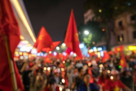 Blurred background of crowd of vietnamese football fans down the street to celebrate the win after soccer with a lot of vietnamese flags raising high