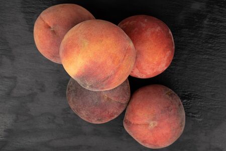 Group of five whole sweet red peach flatlay on grey stone