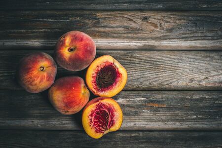 Ripe tasty peaches on a wooden brown surface in vintage style