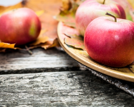 Autumn red apples and maple leaves on old wooden table thanksgiving day concept macro shot very shallow depth of fields Stock Photo