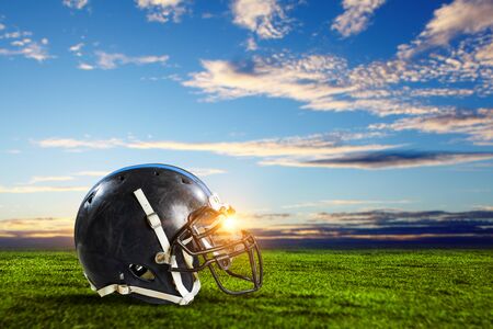 Rugby helmet on green grass and blue sky background mixed media