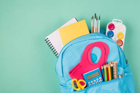 Healthcare concept studies during quarantine concept top above overhead view photo of backpack filled with colorful stationery and mask isolated on turquoise background