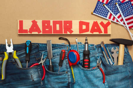 Jeans with tools on masonite plate with duct tape text and us flags top view patriotic holiday concept of labor day Stock Photo