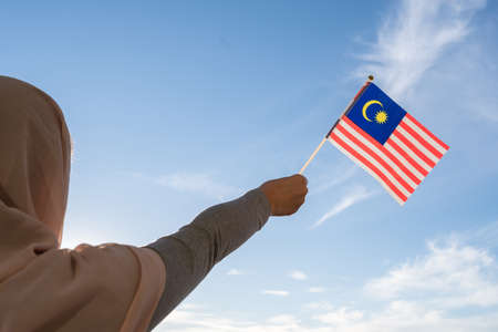 Silhouette of muslim woman in head scarf with malaysia flag at blue sunset sky concept of freedom