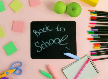 Back to school concept black board with an inscription on a blue background next to colored pencils and stationery study preparation for school banner or postcard for the store flat lay top view