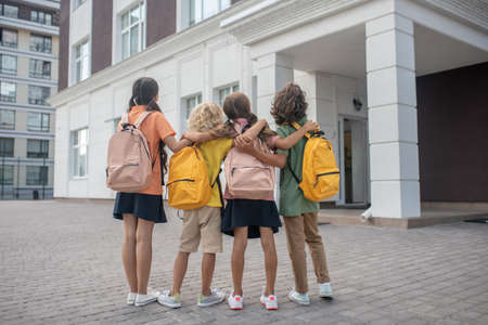 Near school building schoolchildren standing in school yard and looking at school building Stock Photo