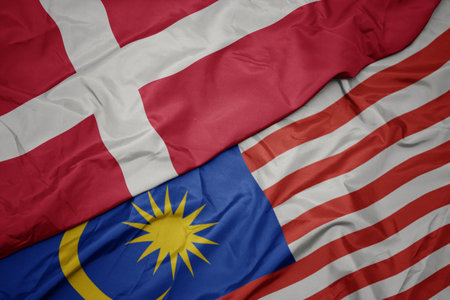 Waving colorful flag of malaysia and national flag of denmark macro