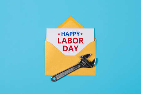 Happy labor day concept yellow envelope and wrench on blue background