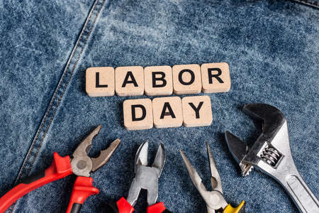 Top view of wooden cubes with labor day lettering near tools on blue denim cloth