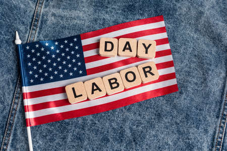 Top view of small usa flag and cubes with labor day lettering on blue denim cloth