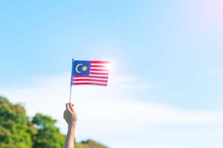 Hand holding malaysia flag on blue sky background september malaysia national day and august independence day