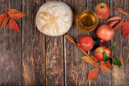 Harvesting concept jewish new year rosh hashanah background autumn composition with apples honey pomegranate and bread on an old wooden table ecological food healthy eating body detoxification selective focus