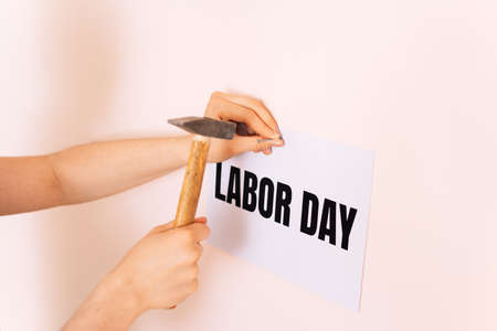 Woman nailing sign to the wall with the words labor day