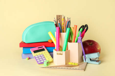 Pen cup with school stationery and apple on yellow background Stock Photo