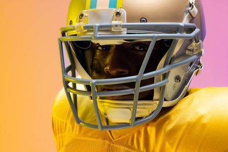 African american male american football player wearing helmet with neon yellow and purple lighting sport movement training and active lifestyle concept