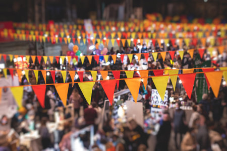 Crowded christmas market with a new year decorations and multicolored flags balloons garlands and festoons xmas fair interior retail sale kiosk and store with illumination