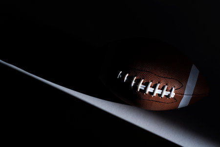 American football ball with natural lighting on dark background horizontal sport theme poster greeting cards headers website and app