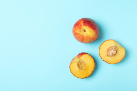 Sweet juicy peaches on light blue background top view space for text