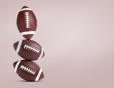 Stack of american football balls on pale pink background space for text Stock Photo